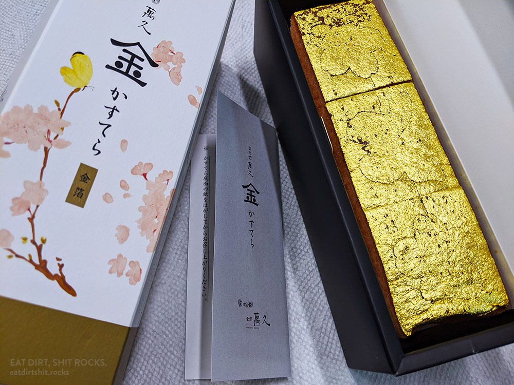 The laser-cut, gold-foil-topped cake intact, along with its packaging.