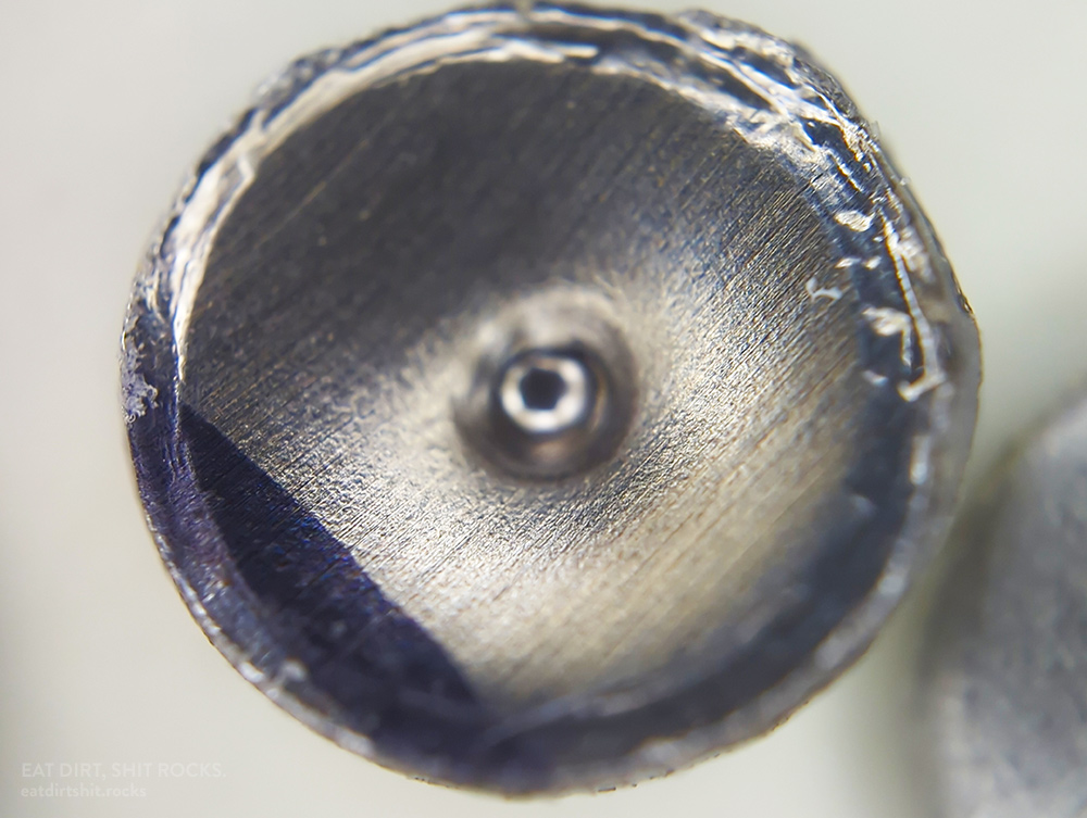 Another 304 stainless steel metal confetto. This one is in concave orientation, with the central bulge facing away from the viewer.