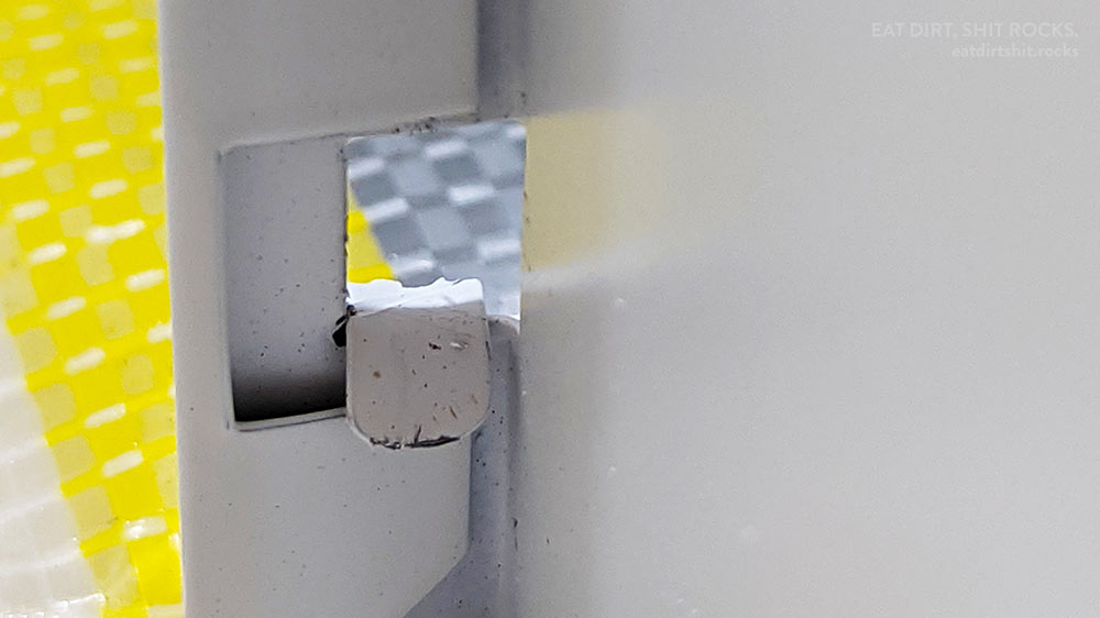 The same tab, bent over and through one of the matching holes stamped or cut into that backwards-pointing flap of a rear drawer panel.